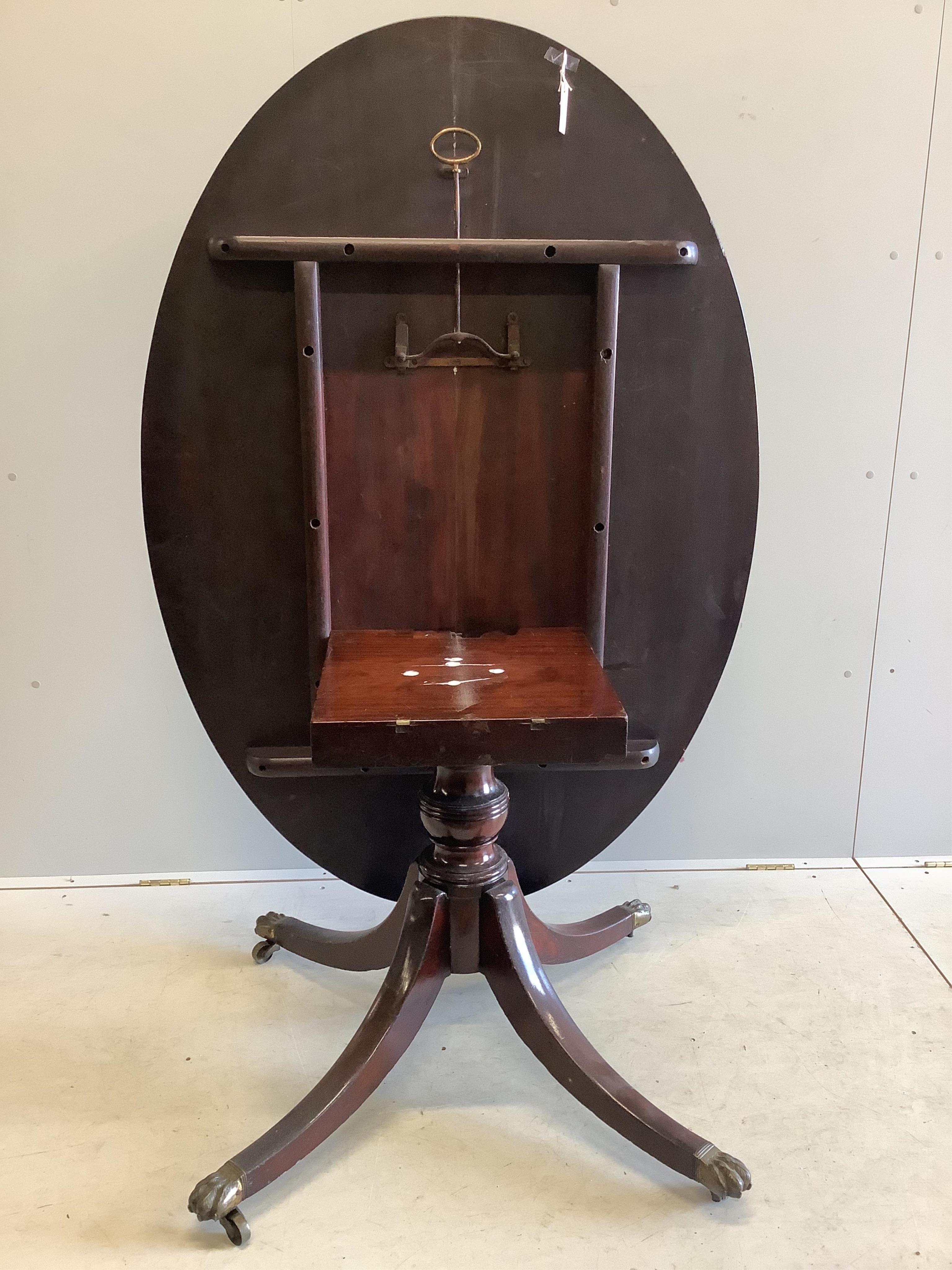 A George III mahogany oval pedestal dining table with brass claw feet, width 152cm, depth 105cm, height 71cm, together with a set of six Regency mahogany sabre leg dining chairs. Condition - fair to good